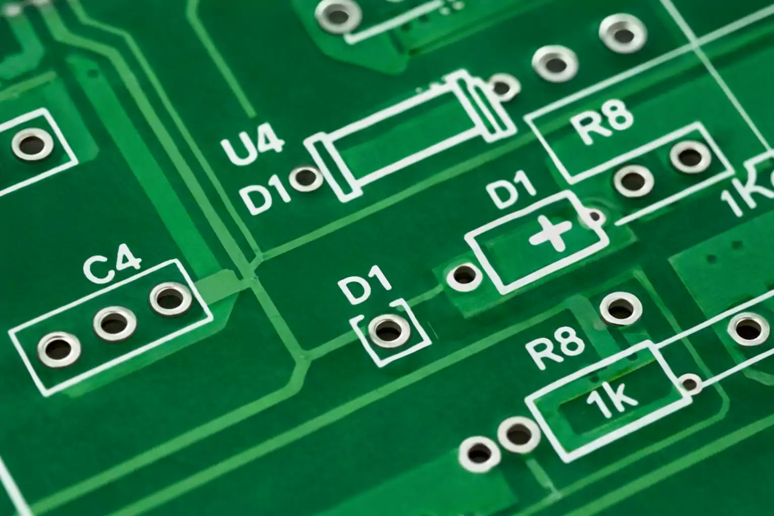 PCB silkscreen close-up showing reference designators, polarity and outlines on a green board.